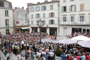 Public massé en cercle sur une place de ville autour des trois interprètes — Le bal des 3 p'tites têtes