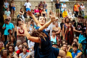 Danseuse bras levés au milieu du public assis sur des gradins de pierre — Fibre