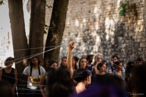 Main levée tendant un fil au-dessus du public, réseau de fils tissés entre les arbres — Fibre