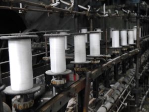 Bobines de fil blanc alignées sur une machine à filer ancienne — Fibre