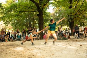 Deux danseuses bras déployés, l'une accroupie, l'autre debout, sur le sol sableux d'un parc — Hors Sol