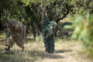 Deux silhouettes en costumes de fibres végétales dans la garrigue, une main levée vers le ciel — Hors Sol
