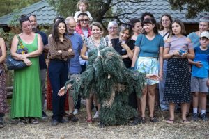 Interprète en costume de fibres vertes courbée devant le public debout en demi-cercle — Hors Sol