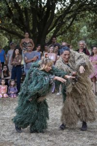 Deux interprètes en costumes de fibres, vert et beige, penchées vers le sol devant les spectateurs — Hors Sol