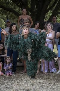Danseuse émergeant d'un costume de fibres vertes, bras écartés, regard levé — Hors Sol