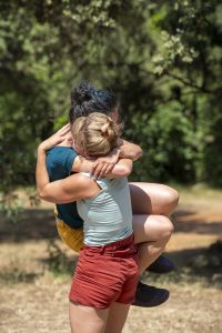 Danseuse portée dans les bras de sa partenaire, visages enfouis, en sous-bois — Hors Sol