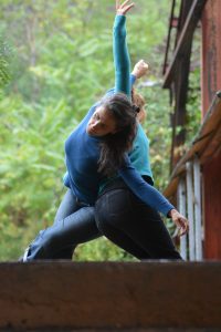 Danseuse bras levé sur une passerelle métallique rouillée, végétation en arrière-plan — Hors Sol