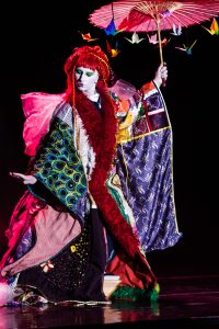 Interprète en kimono d'étoffes multicolores, perruque rouge et ombrelle garnie de grues en papier — Kimonoshima