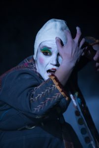 Visage maquillé de blanc au fard vert, une main devant l'œil, sur scène — Kimonoshima