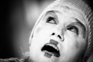 Gros plan d'un visage maquillé de blanc, bonnet de tissu et bouche ouverte, en noir et blanc — Kimonoshima
